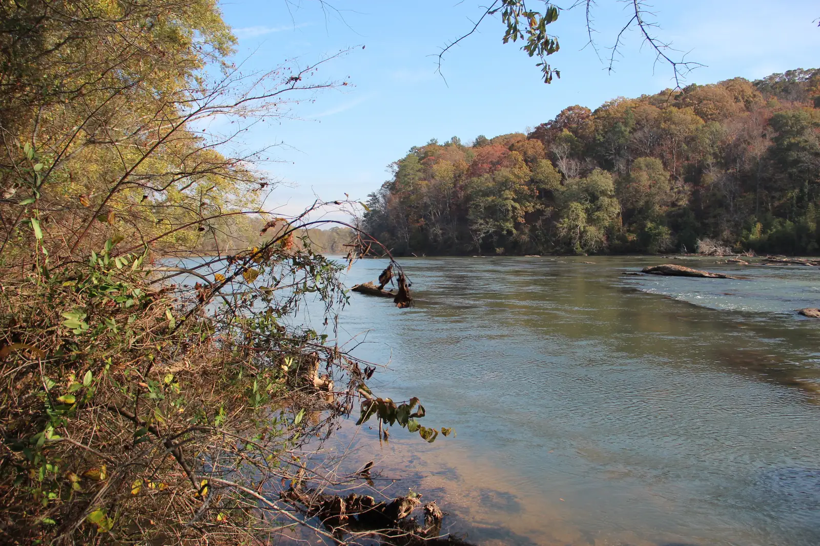 The Chattahoochee River at Cochran Shoals in autumn, with orange and red trees on the far bank
