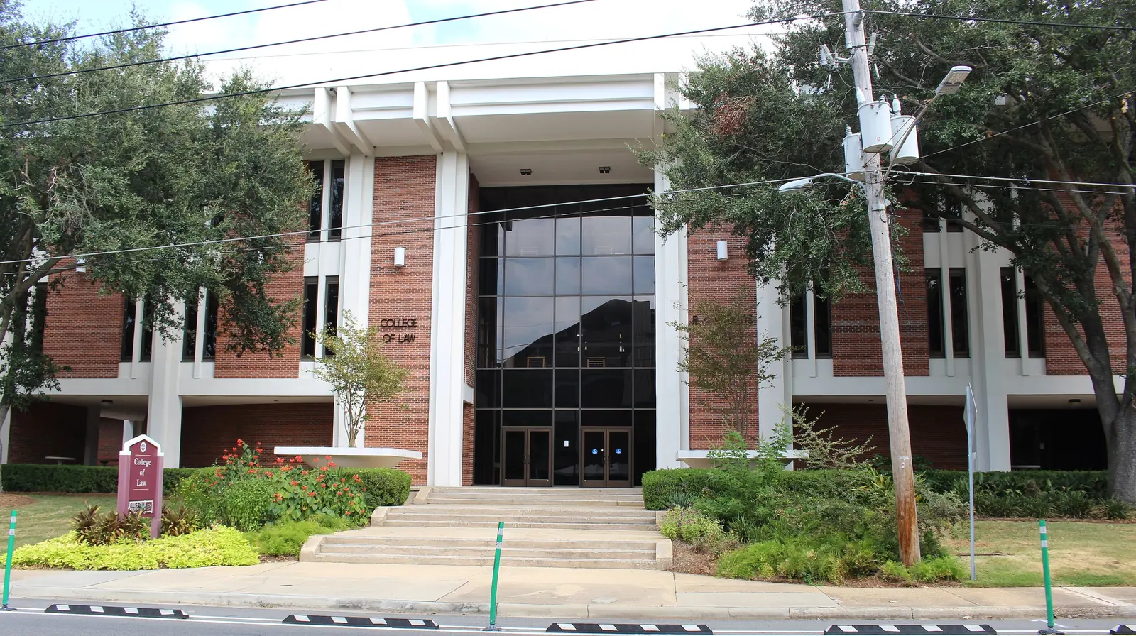 The FSU College of Law building in Tallahassee, red brick and white columns behind live oaks